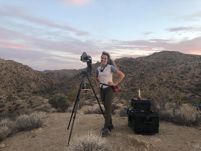 young woman standing with field equipment at dusk