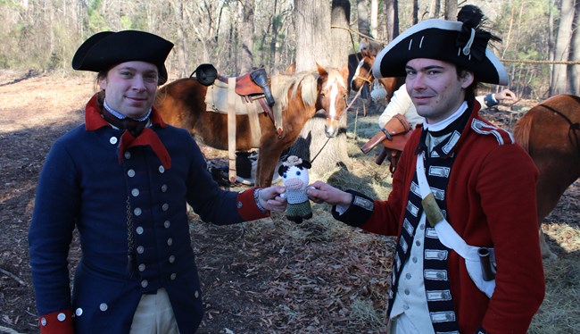 Reenactors in blue and red uniforms hold ranger cow