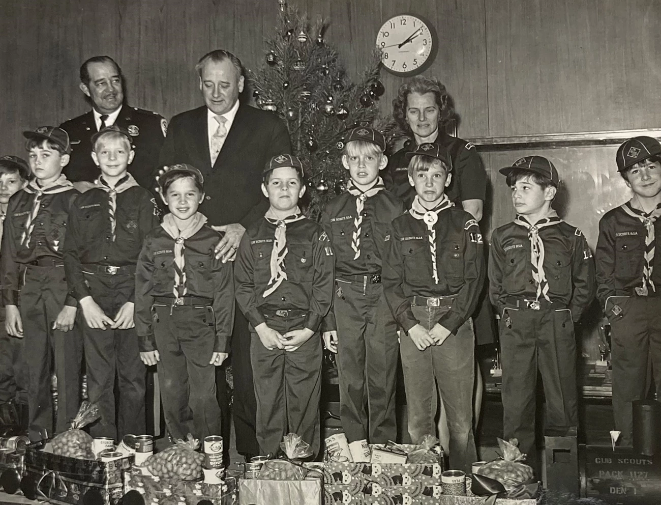 Boy Scout donation Three adults stand behind a troop of boy scouts standing in front of a train made of presents