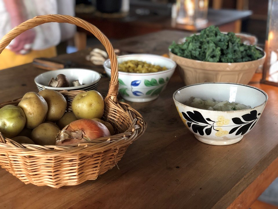 Fort Vancouver Kitchen Ingredients Potatoes, onions, and other ingredients in baskets and bowls on a table.