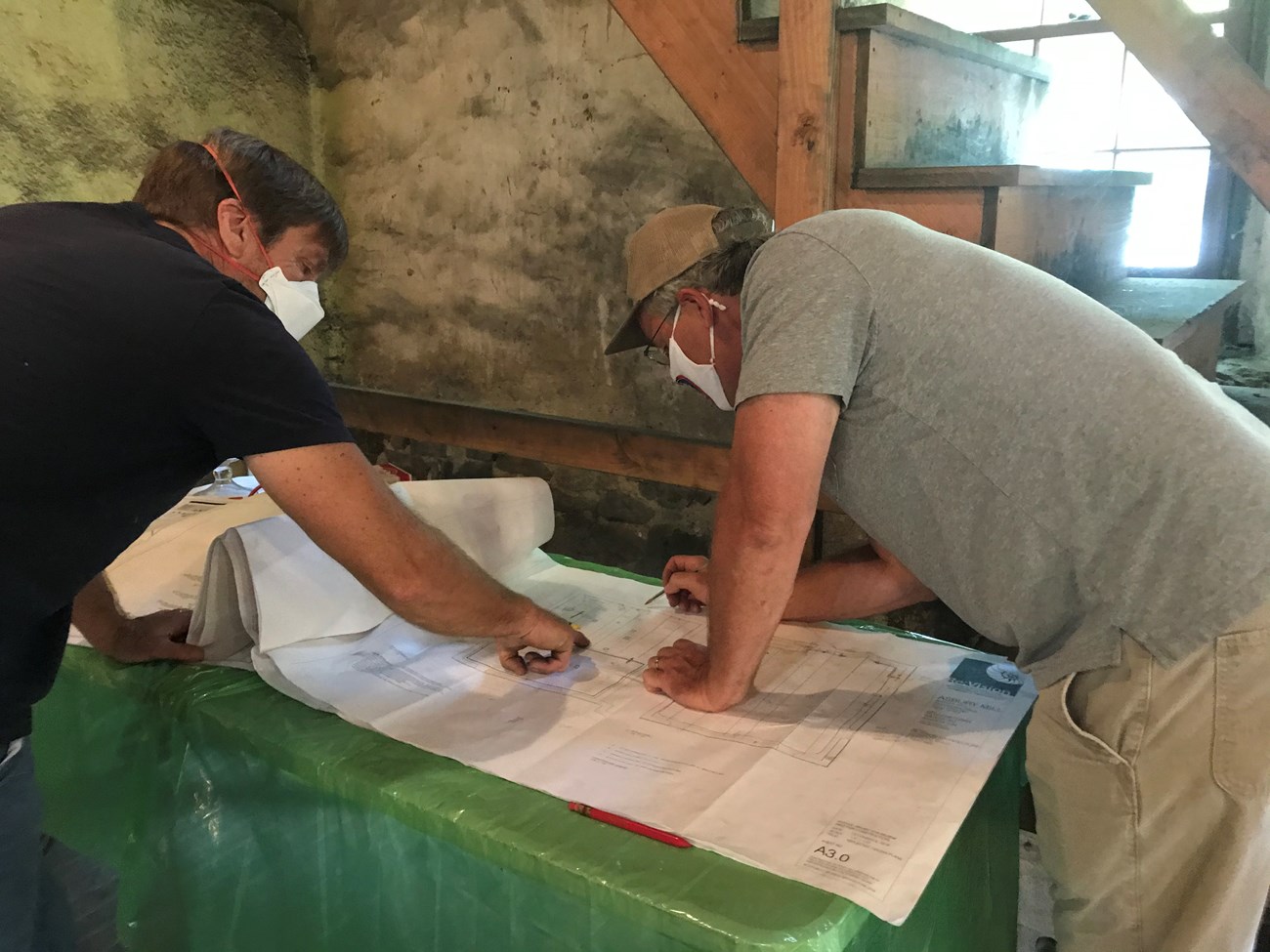 Ray Mulvey, Electrician (Mulvey Electric), and Paul Schroeck, Construction manager (Windward Environmental), look over the plan to install code-required safety lighting as Asbury Mill is restored.  Photo courtesy of Alan Hunt and the Musconetcong Watershe