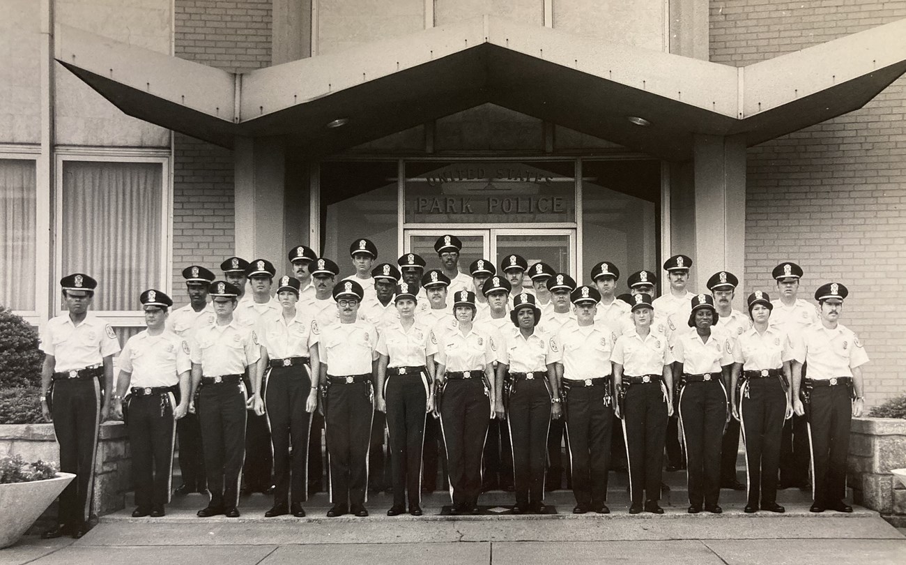US Park Police officers in uniform stand in rows, posing for a class photo