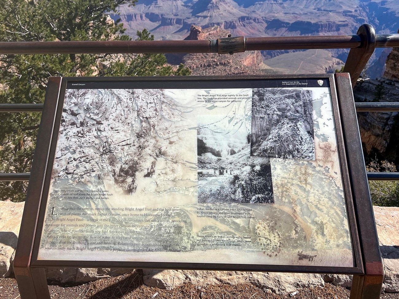 IMG_7759 copy a faded exhibit panel that is not legible. In the background colorful peaks and cliffs are visible within a canyon landscape