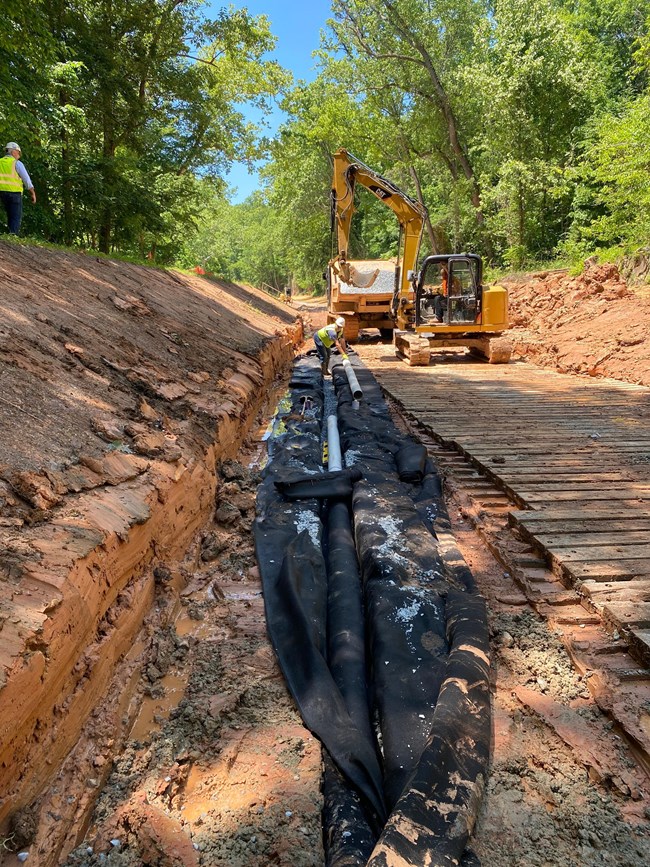 A long pipe set in a black liner within a clay canal prism
