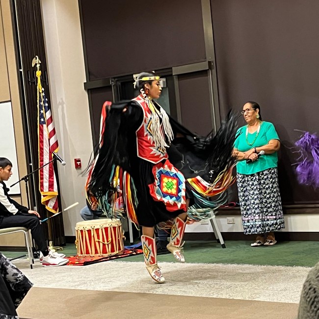 A girl dances in traditional Native American ceremonial clothing with fringes