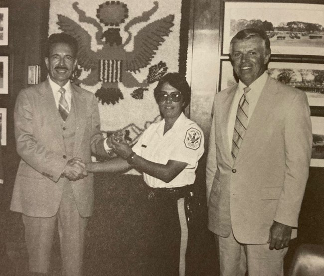 Valerie Fernandes in uniform stands between two men in suits.