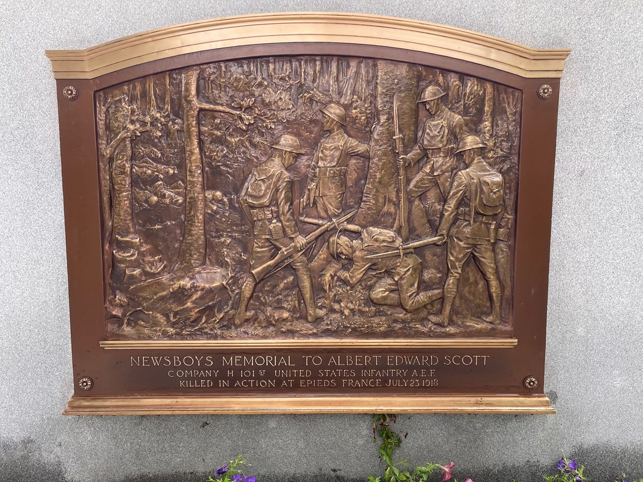 Metal plate showing five soldiers in a wooden area with one soldier on his knees and the others standing around him.