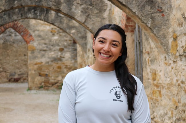 CLA Daniela Woman standing smiling under stone arches