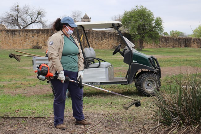 Apprentice Sarah uses a weed wacker on the landscape at the Visitor Center