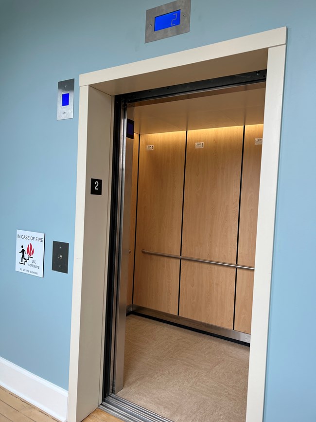 An open elevator door is surrounded by blue painted walls.