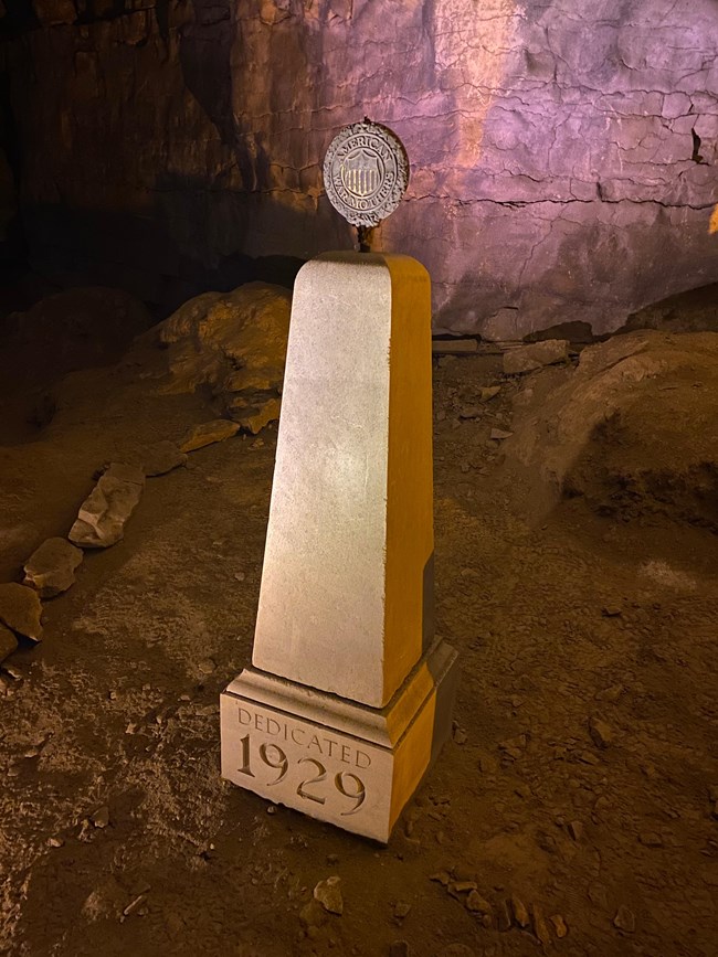 A stone monument with the date 1929 and a round metal plaque on the top.