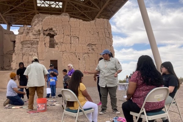 A group of visitors and volunteers complete an activity next to a ruin.