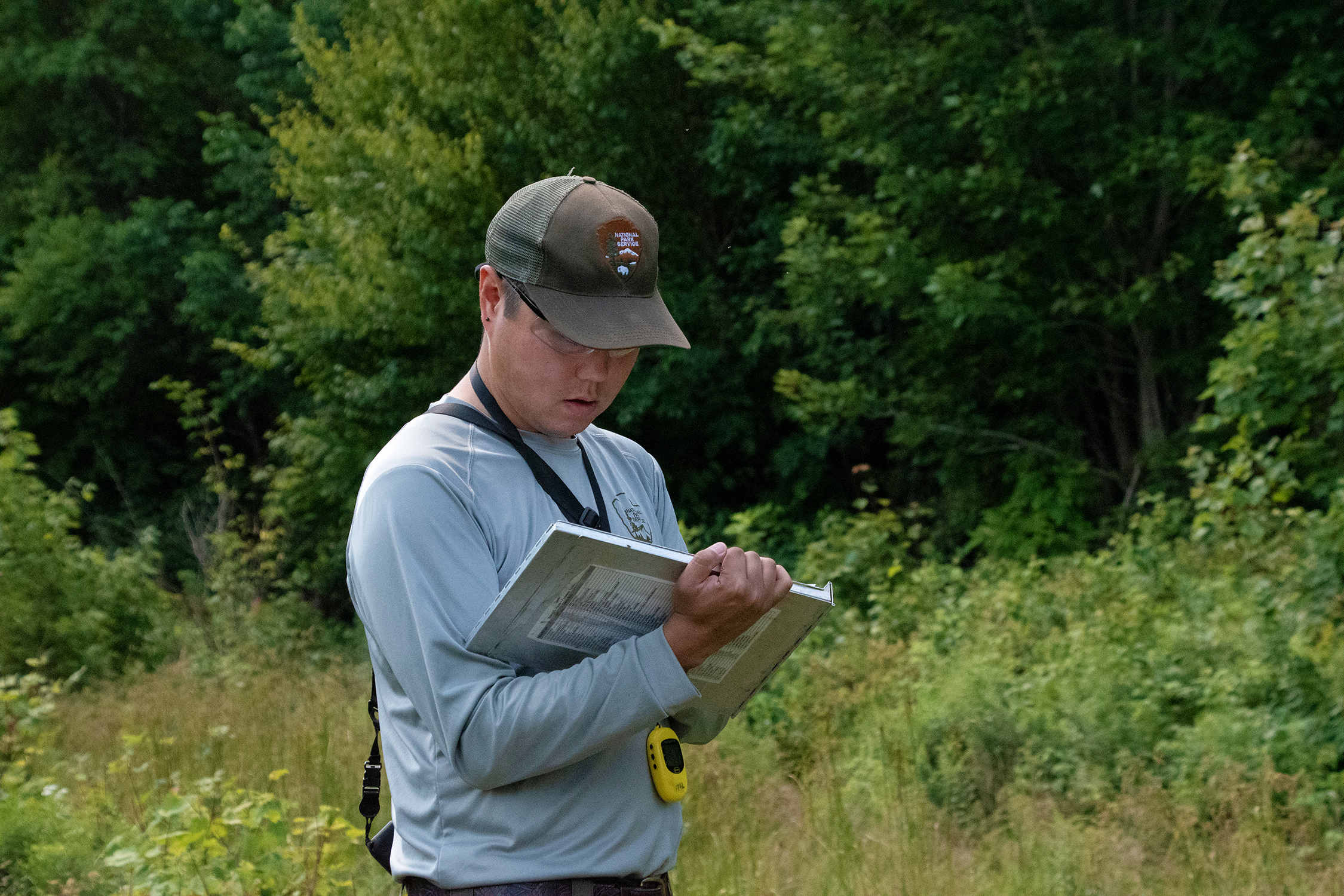 A man in an NPS uniform and ball cap looking at a metal pad