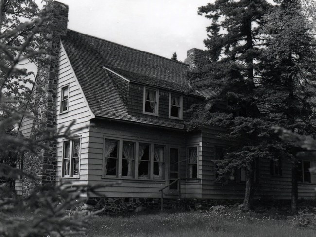 Davidson Residence two story house with stone chimney, siding, stone foundation and many windows