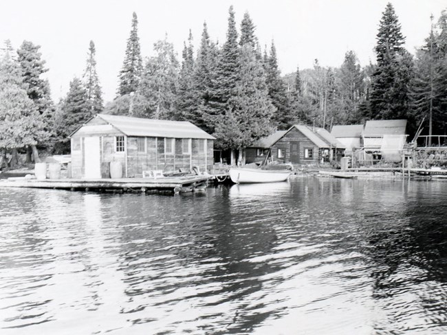 Bangsund Fishery fish house on left over waterway, cabin behind it, net racks on right