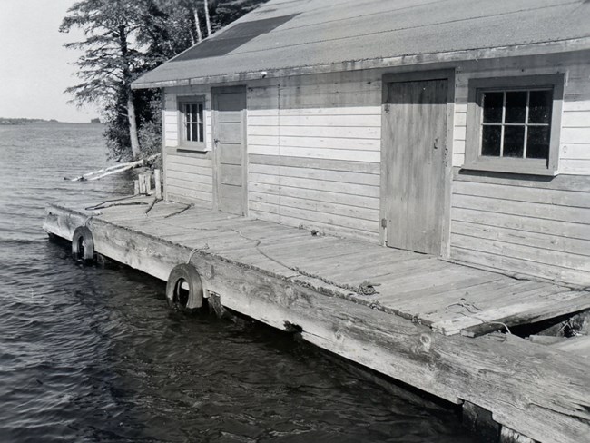 fish house with two windows and two doors, dock in front
