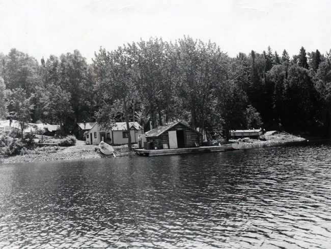 Edisen Fishery shoreline of fishery, boat pulled up on ramp next to fish house, cabin in back