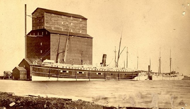 SS Algoma docked at Port Arthur, ON with tall building towering behind it