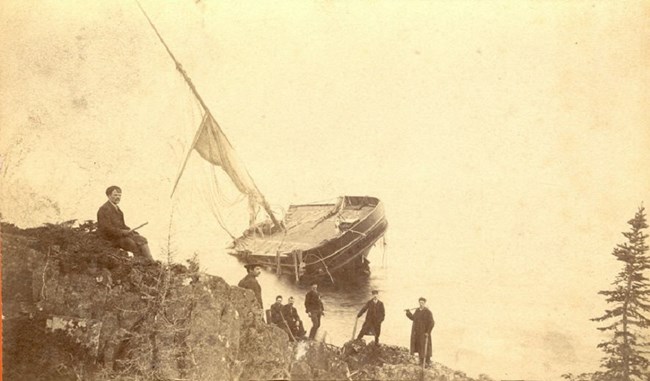 men looking on as miniscule remains of SS Algoma sink into Lake Superior