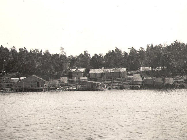 fishing cabins, many nets drying, boats at shore