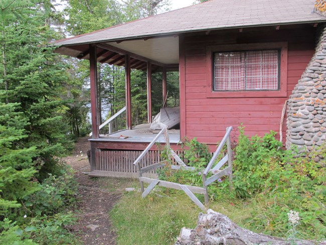 red cottage with boat resting on large covered front porch