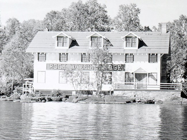 three level lodge structure on waterfront with large letters emblazoned on exterior