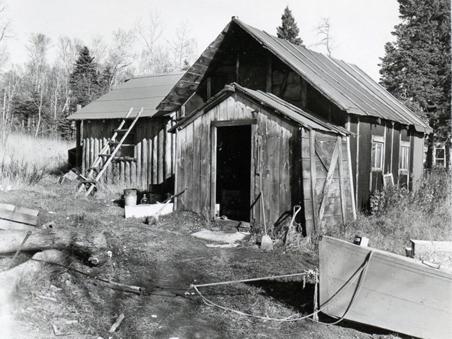 fishing cabin, boat out front, ladder going up to roof