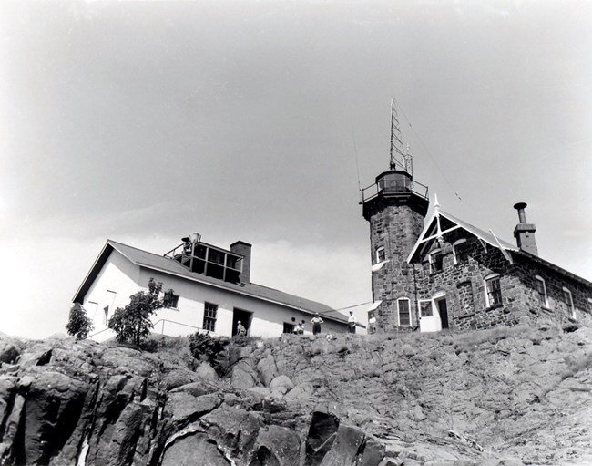 visitors in front of the Passage Island lighthouse, facility doors open for tour