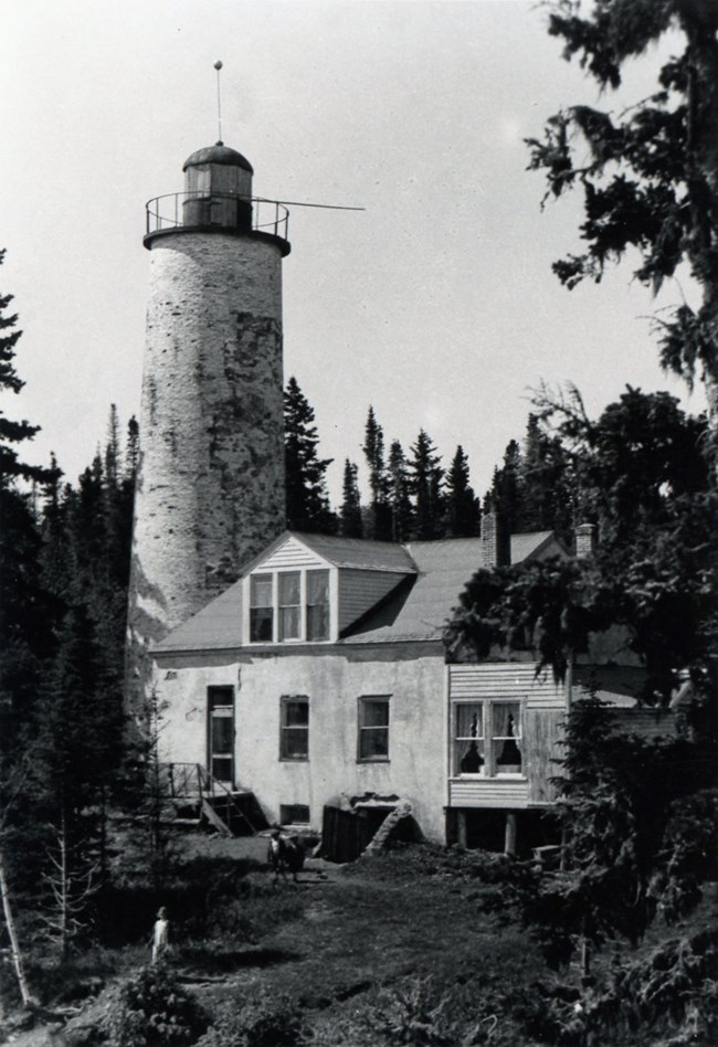 The Rock Harbor Lighthouse at a point of being inhabilted with curtains in the windows and the cellar door being utilized for storage.