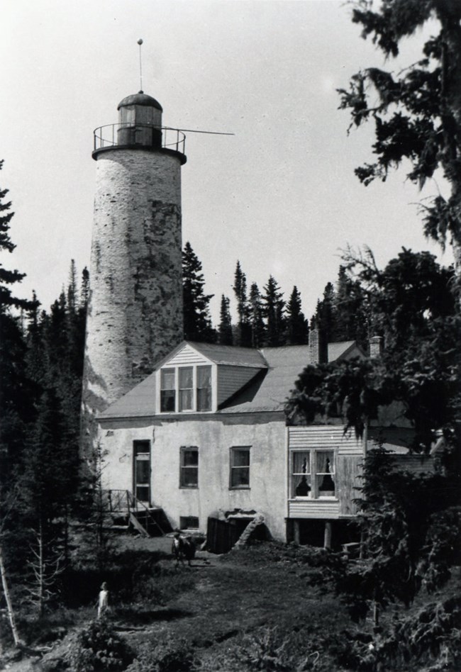 Rock Harbor Lighthouse The Rock Harbor Lighthouse at a point of being inhabilted with curtains in the windows and the cellar door being utilized for storage.