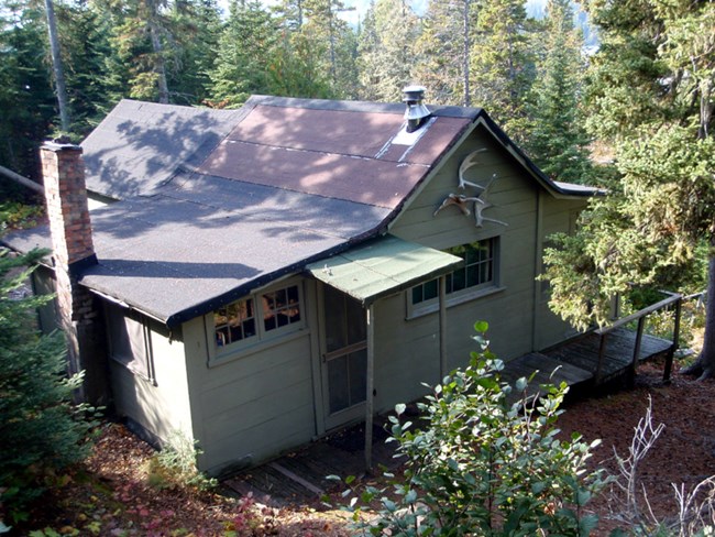 tar paper roofed green cottage with covered back door