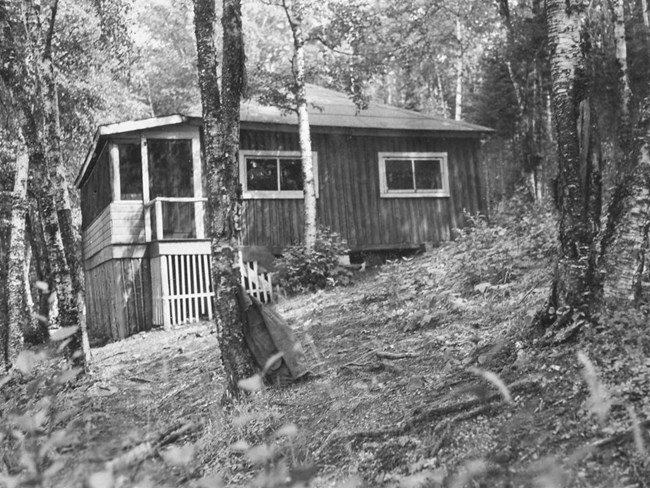 wood sided cabin with large covered porch on left side