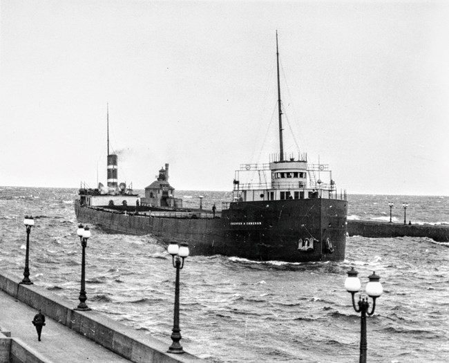 SS Chester A. Congdon arriving to a dock with lampposts on the left and a person looking on from the dock
