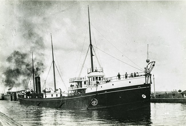 SS William H. Gratwick navigating through a harbor with crew looking out from deck