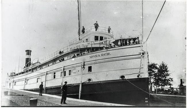 SS Monarch docked with many passengers looking out from the bow
