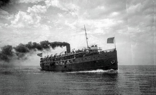 USS Puritan, flying flags at bow and stern as it sails the lakes