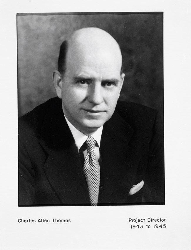 Identification Plate Charles Allen Thomas, Project Director, 1943-1945 Balding white male wearing a suit. Text includes Charles Allen Thomas, Project Director 1973-1975.