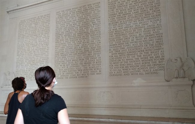 Two young visitors looking up the inscription of Lincoln's speech on the marble wall of the Memorial