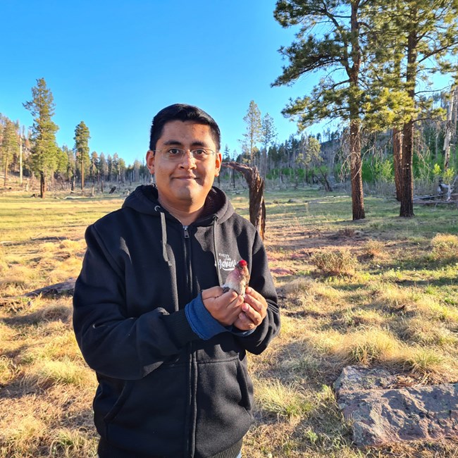 lt= Erwin Lopez Osario holding a Cassin's finch
