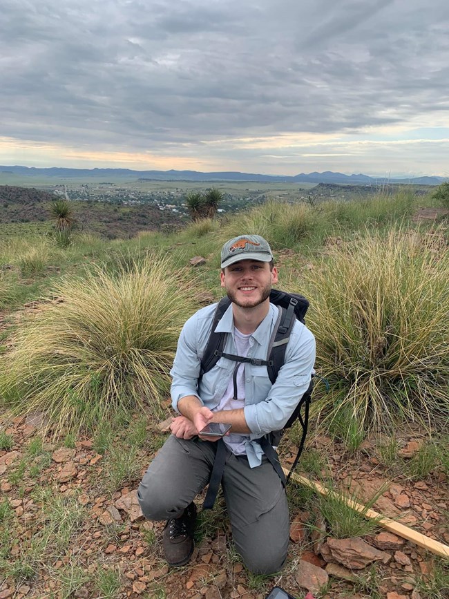 Wesley crouching down with his equipment in a desert