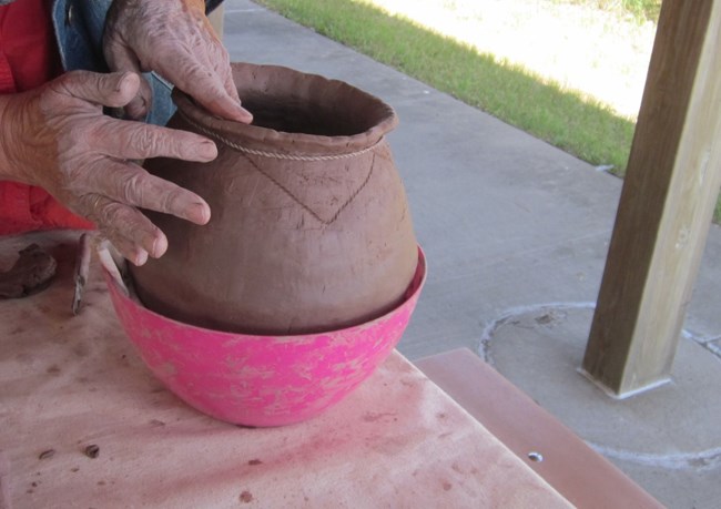 Hands making a clay pot