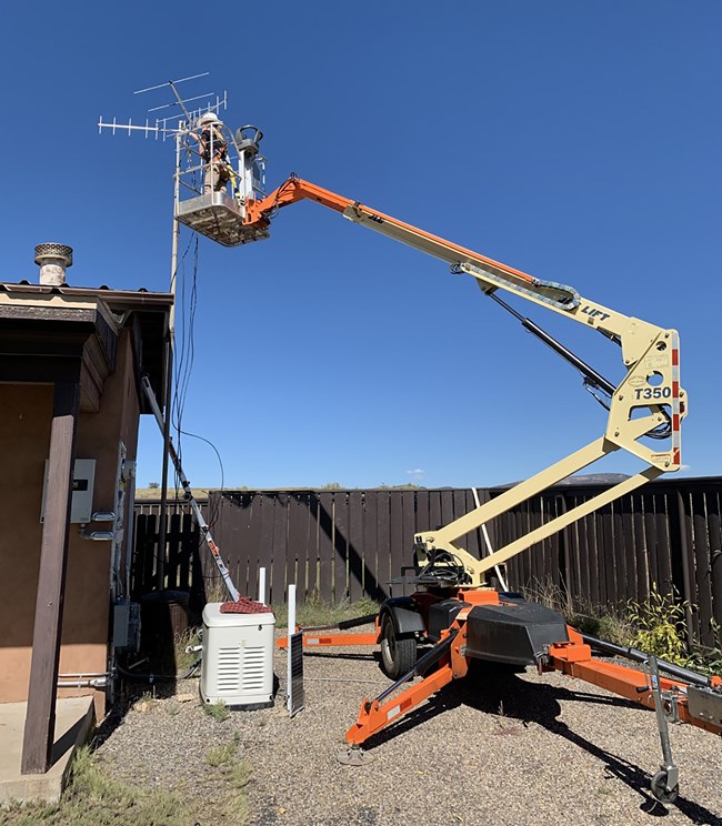 Man on a forklift installing antenna on the roof of a building