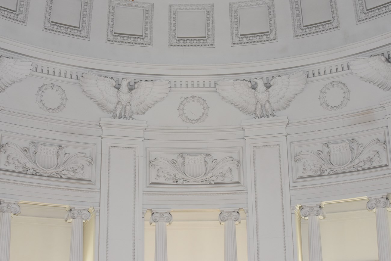 White domed ceiling with eagles ornamented along the bottom ring of dome curve