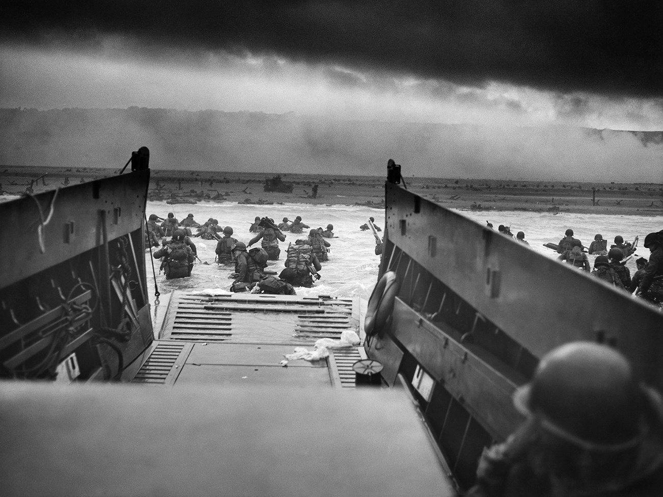 Soldiers on a boat approaching shore ready for battle.