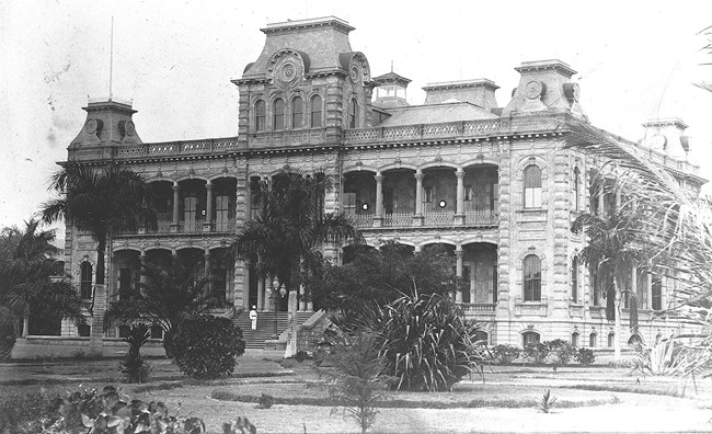 Grey scale photo of large two story palace with towers on corner and in the center