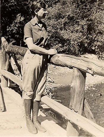 Isabel_Bassett_Wasson_on_bridge Isabel Bassett Wasson wearing breeches, boots, and a blouse stands on a bridge, looking into the distance.