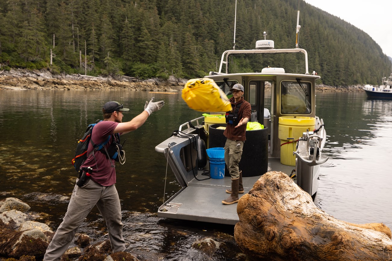 Volunteers load bags of marine debris onto a boat for disposal. Volunteers load bags of marine debris onto a boat for disposal.