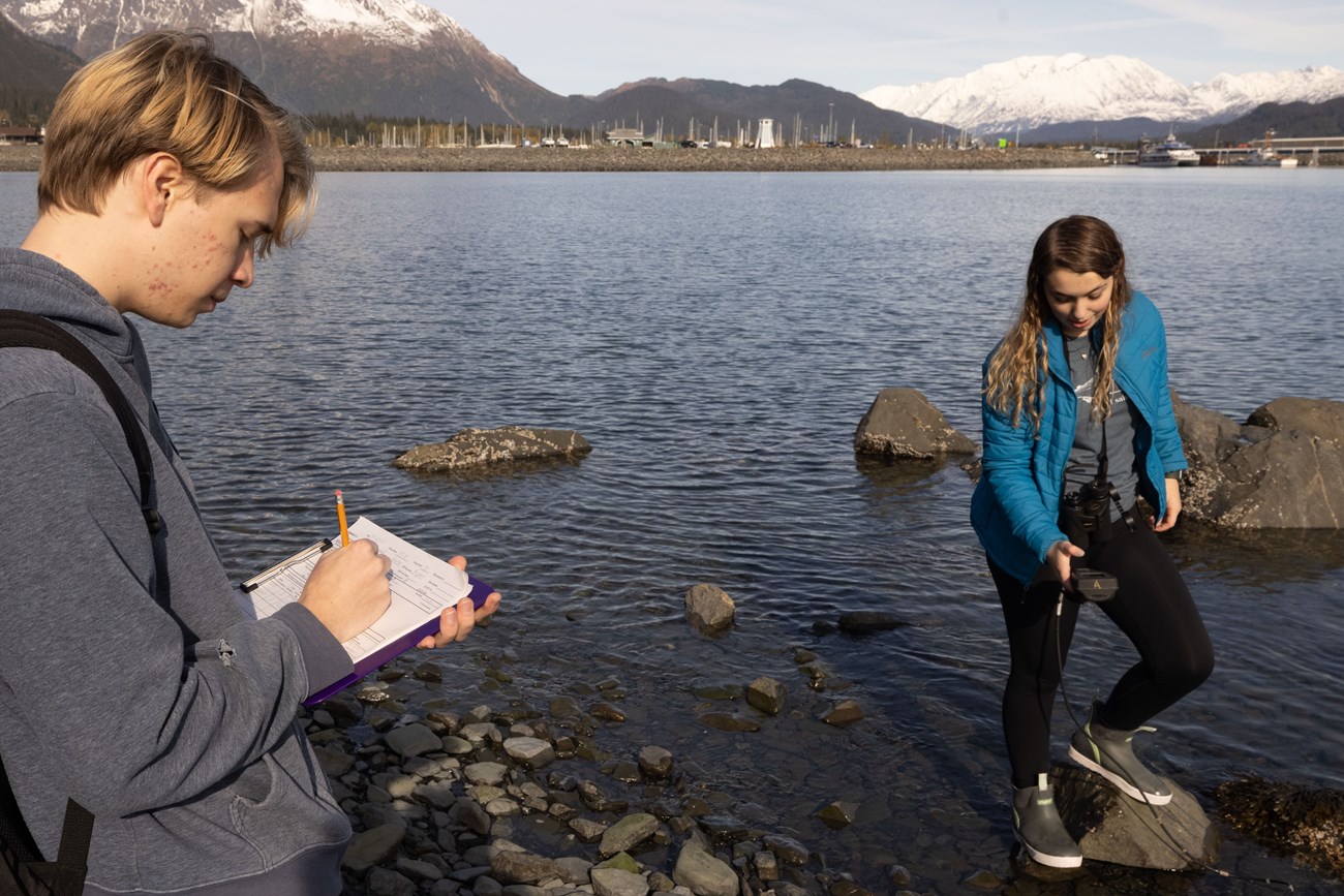 Two Seward High School students sample and record water quality in the Seward Harbor.