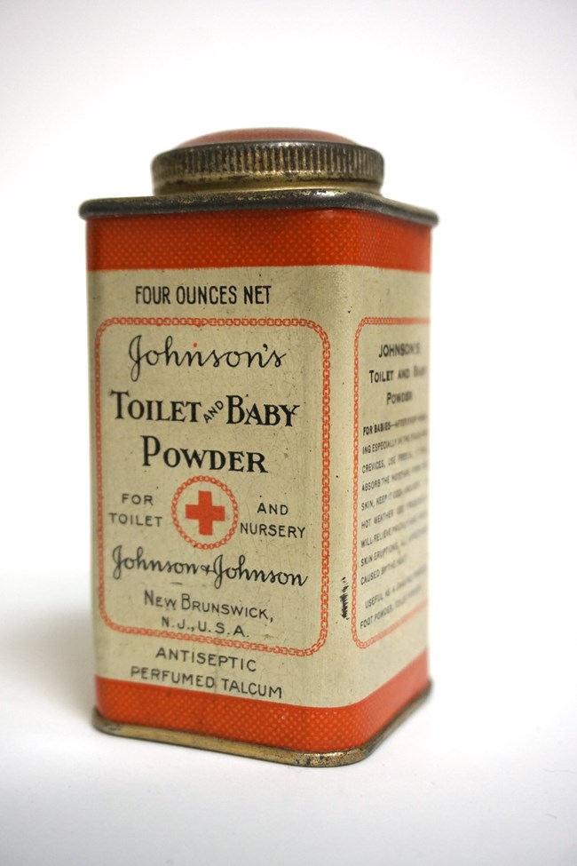 A small rectangular tin of baby powder.  The label is red and white.  A circular screw top lid sits atop the canister.