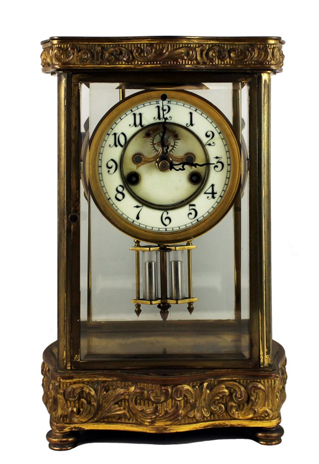 Shelf clock with rectangular gilded case, glass front, and white enamel face.